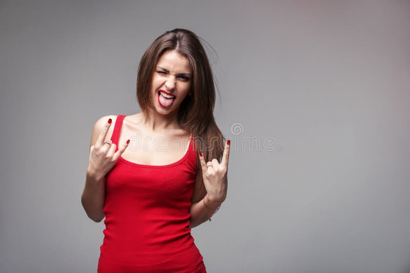 Young brunette woman showing rock and roll hand gesture posing in studio.