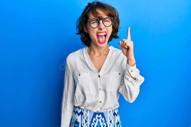 Young brunette woman wearing casual clothes and glasses pointing finger up with successful idea