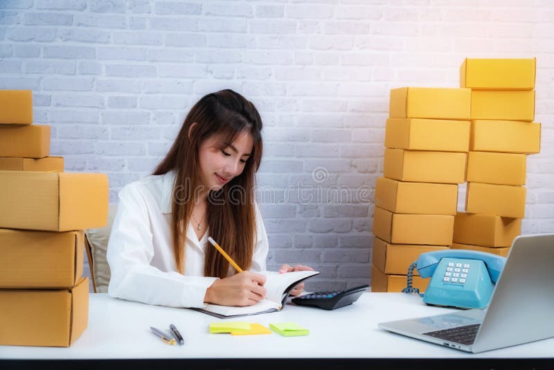 Young business entrepreneur owner write in the delivery in notebook about online delivery business. online shopping SME royalty free stock image Young business entrepreneur owner write in the delivery in notebook about online delivery business. online shopping SME royalty free stock image