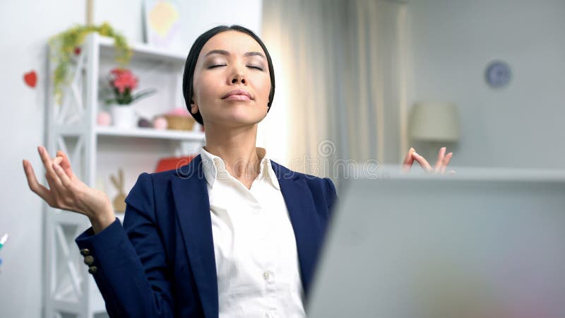 Young business lady meditating front laptop reducing stress, relaxing technique