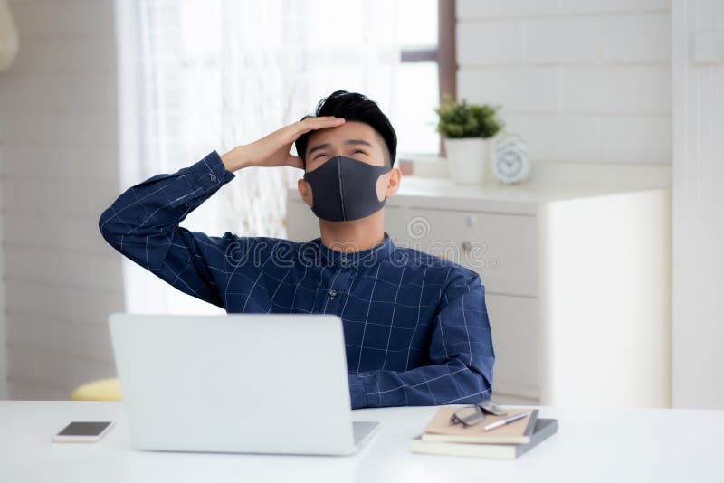 Young business man in face mask working from home with laptop computer and bored on desk for protection for outbreak of covid-19. royalty free stock photo Young business man in face mask working from home with laptop computer and bored on desk for protection for outbreak of covid-19. royalty free stock photo