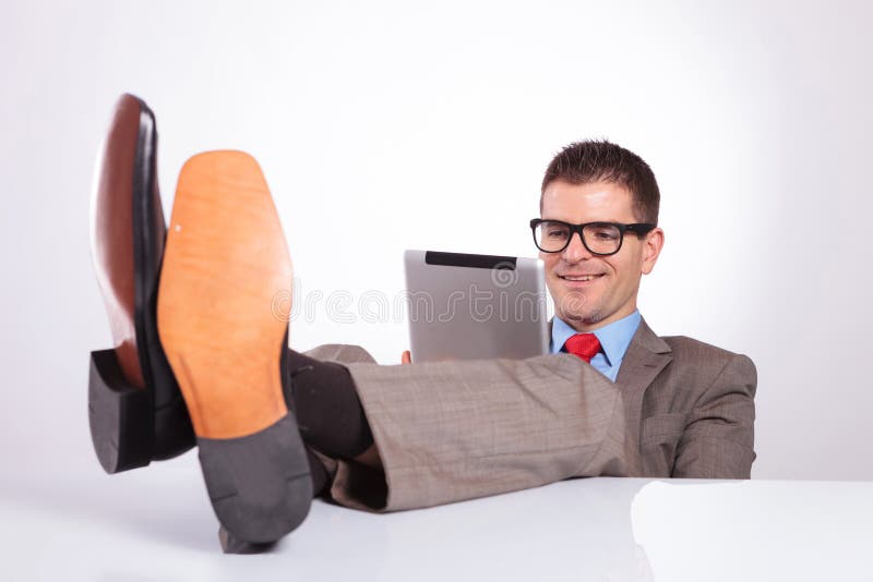 https://thumbs.dreamstime.com/b/young-business-man-smiles-tablet-feet-desk-looking-his-smiling-holding-his-gray-background-34738392.jpg