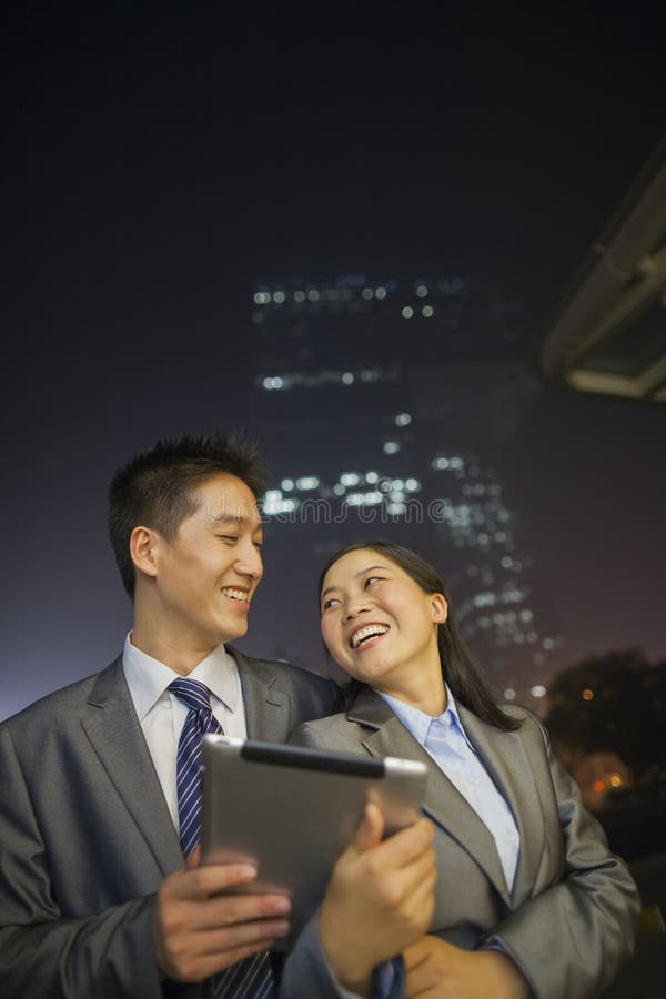 Young business people smiling and holding digital tablet, night and outdoors royalty free stock photography Young business people smiling and holding digital tablet, night and outdoors royalty free stock photography
