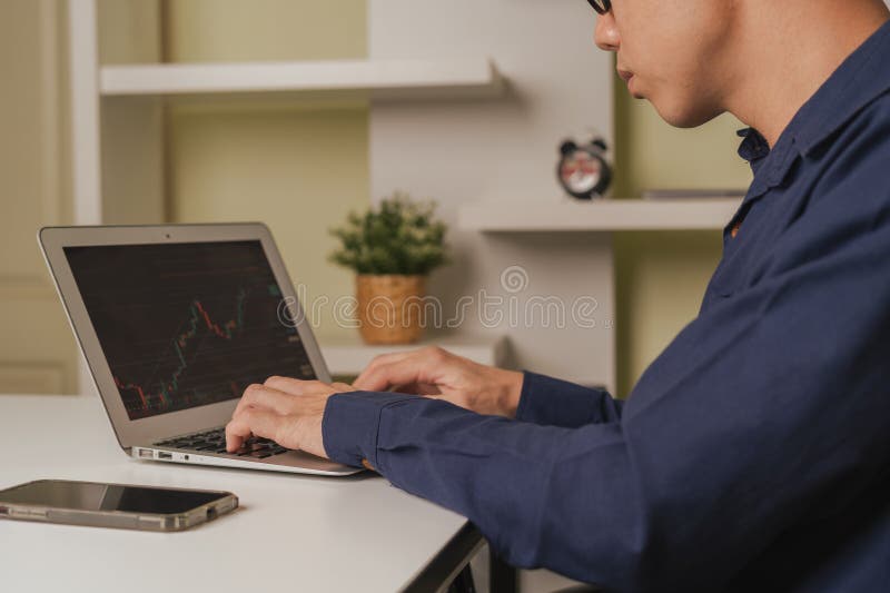 Young business trader or investor man is using stock market chart ticker, Cryptocurrency graph as Bitcoin graphs on device as stock images
