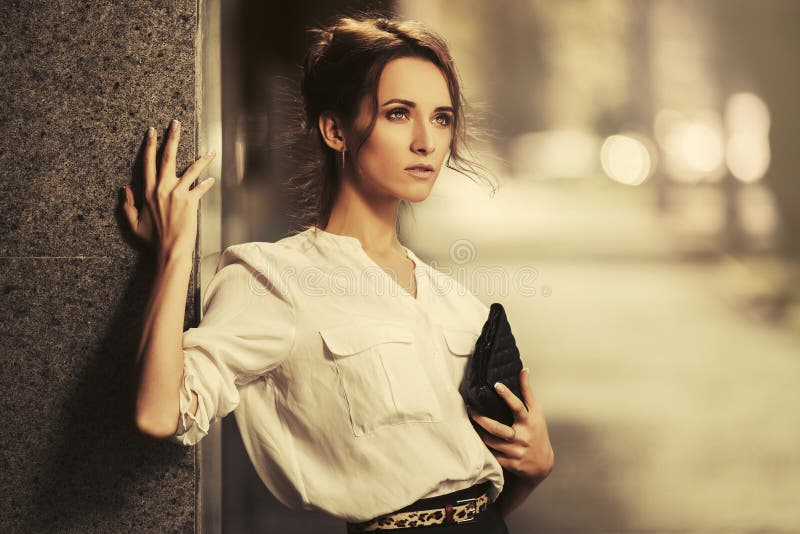 Young fashion business woman in white shirt with clutch bag