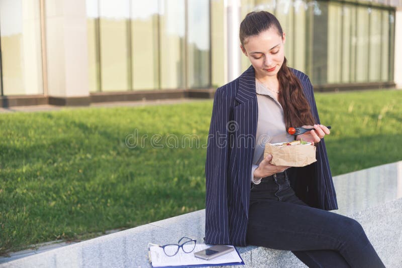 Young business woman eating salad on lunch break in city