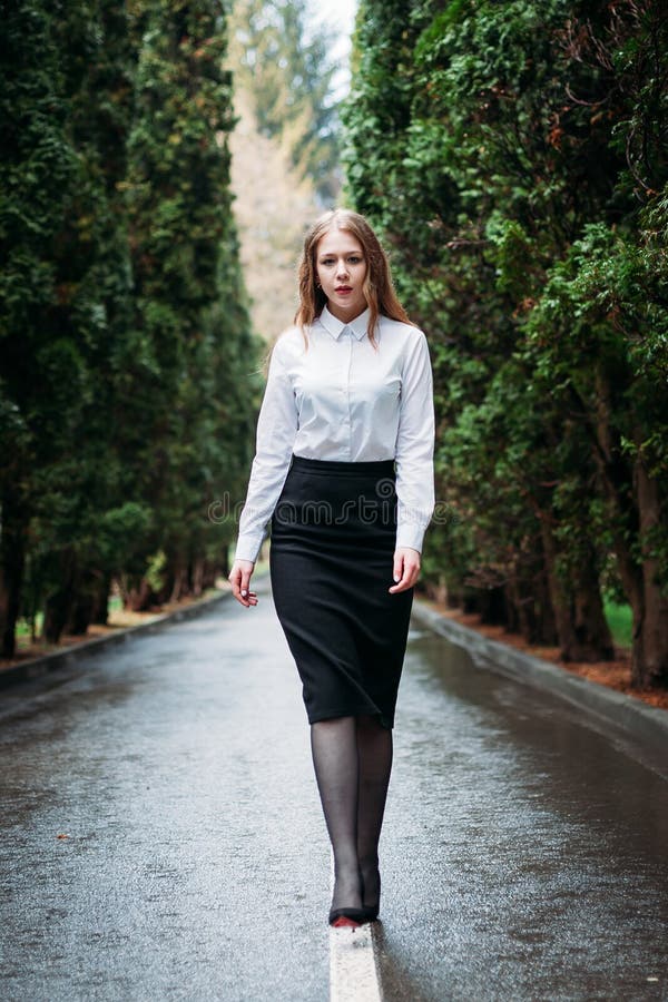 Young business woman in skirt posing outdoors in rain