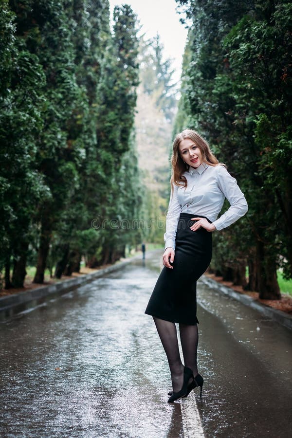 Young business woman in skirt posing outdoors in rain