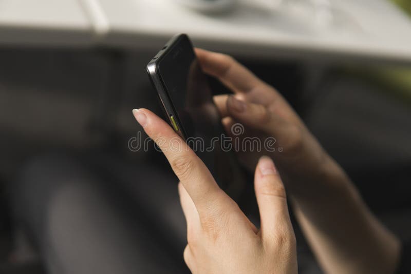 Young business woman uses phone. Good looking brunette female uses online banking on smart phone to transfer money from credit card. Girl using smart phone and chatting with business partners