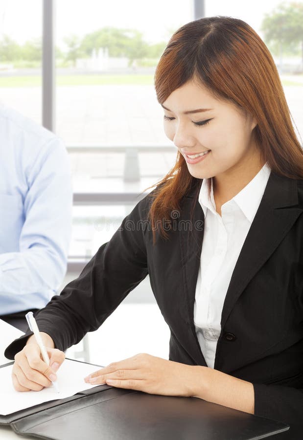 Young business woman writing document with colleague stock photography Young business woman writing document with colleague stock photography