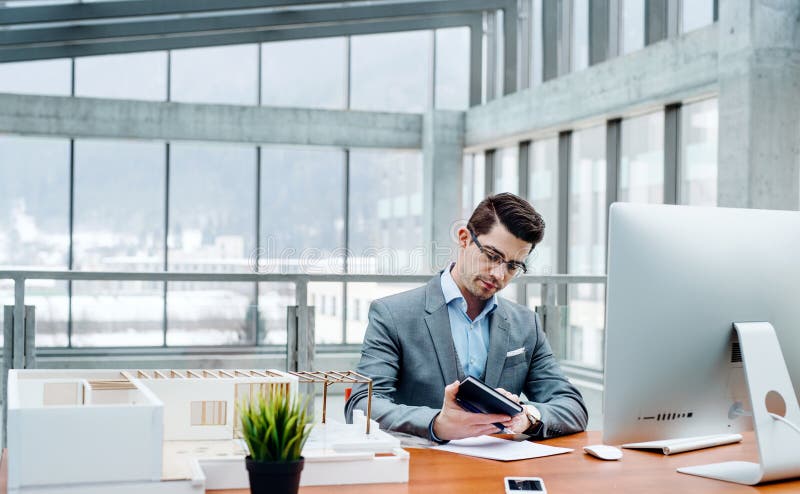 Young businessman or architect with model of a house sitting in office, working. stock photos Young businessman or architect with model of a house sitting in office, working. stock photos
