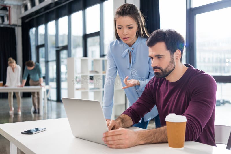 Young businessman and businesswoman working with laptop in small business office royalty free stock photo