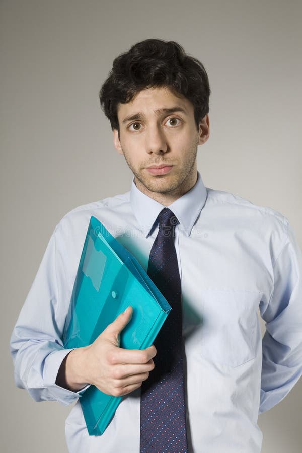 Portrait of an unhappy young businessman holding documents isolated over grey background