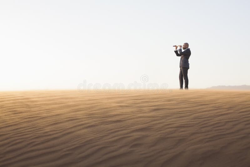 Young businessman looking through telescope in the middle of the desert royalty free stock photography
