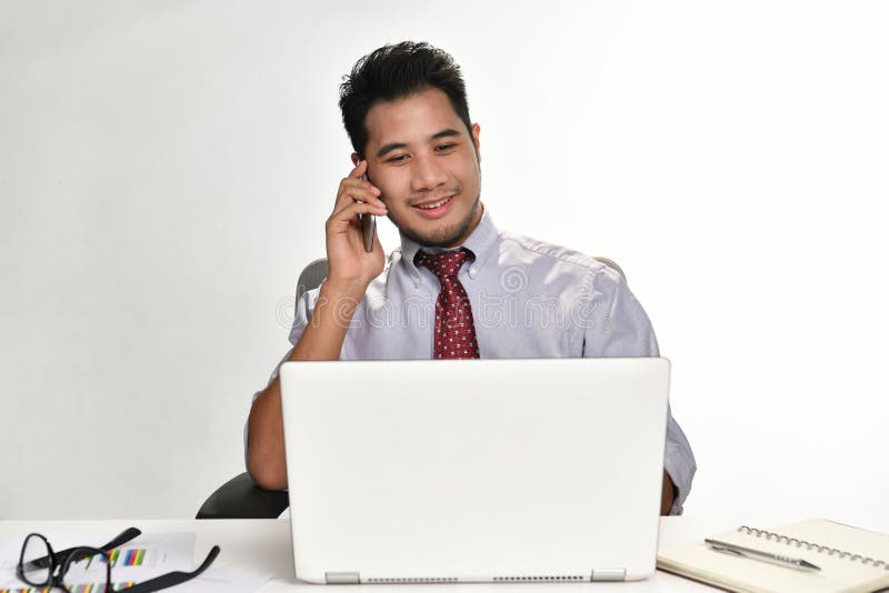 Businessman smiling while talking on the phone and working with laptop computer