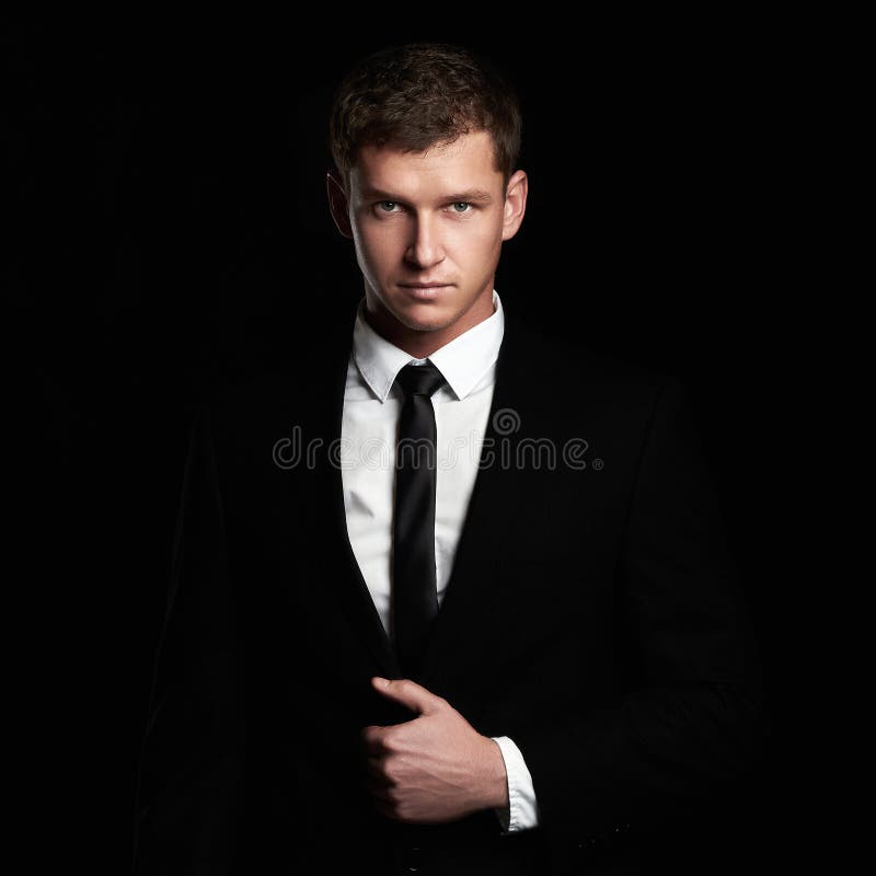 Young Businessman standing on black background. handsome Man in suit and tie