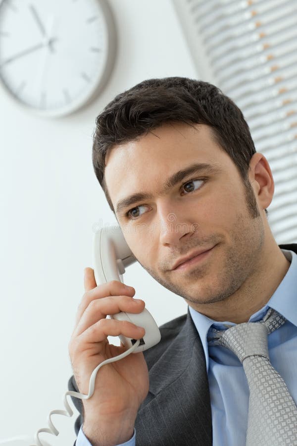 Young businessman talking on landline phone royalty free stock image