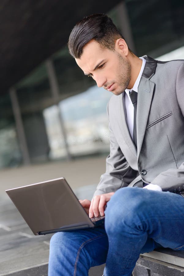 Young businessman typing in a laptop computer in urban background