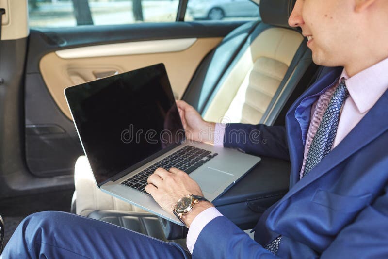 Young businessman using laptop in back seat of car stock photography