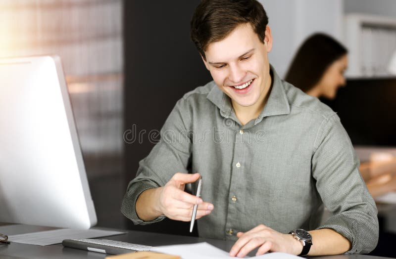 Young businessman working on his computer sitting at the desk in office. Headshot portrait of a man stock photography