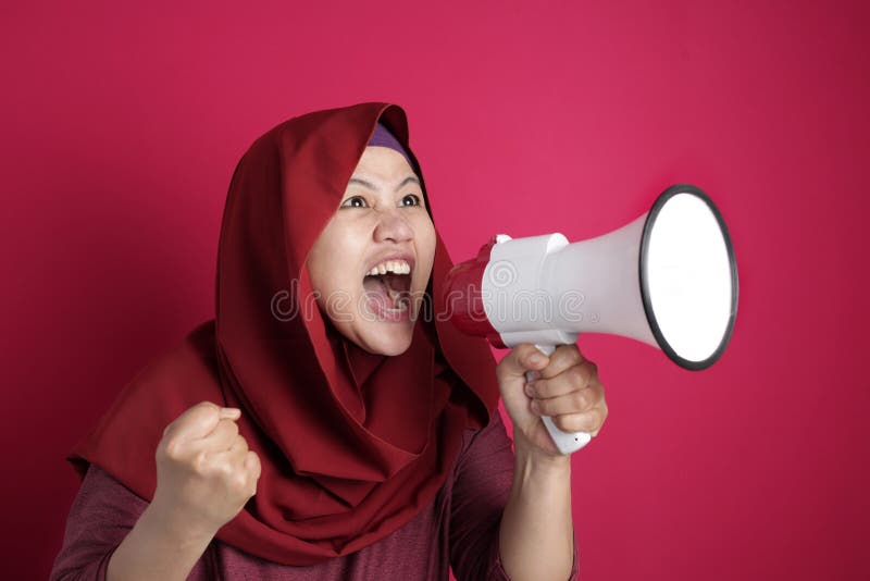 Young Asian muslim businesswoman wearing hijab screaming with megaphone, angry expression. Close up body portrait. Young Asian muslim businesswoman wearing hijab screaming with megaphone, angry expression. Close up body portrait