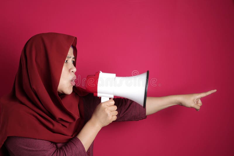 Young Asian muslim businesswoman wearing hijab screaming with megaphone, angry expression. Close up body portrait. Young Asian muslim businesswoman wearing hijab screaming with megaphone, angry expression. Close up body portrait