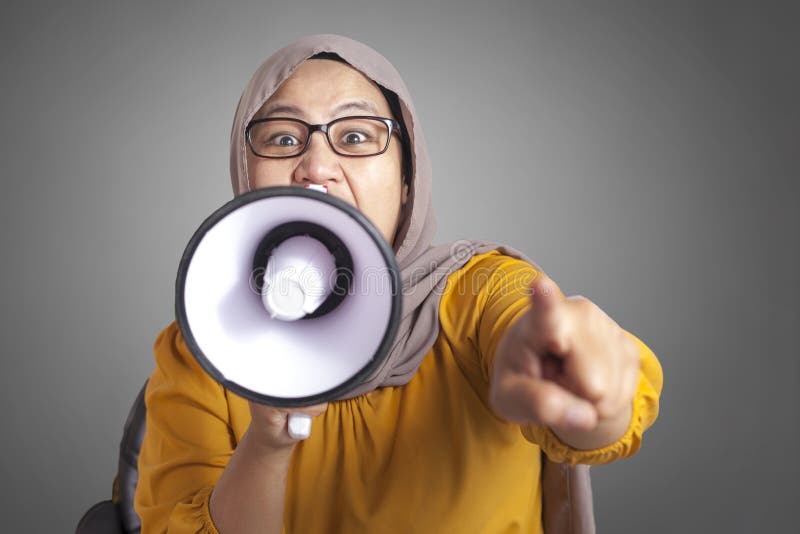 Young Asian muslim businesswoman wearing hijab screaming with megaphone, angry expression. Close up body portrait veil indonesian malaysian arab loudspeaker person female communication people corporate message shouting broadcasting formal manager speaking worker voice talking holding entrepreneur yelling attention news professional executive sound woman adult suit crazy job speech glasses employee pointing looking camera. Young Asian muslim businesswoman wearing hijab screaming with megaphone, angry expression. Close up body portrait veil indonesian malaysian arab loudspeaker person female communication people corporate message shouting broadcasting formal manager speaking worker voice talking holding entrepreneur yelling attention news professional executive sound woman adult suit crazy job speech glasses employee pointing looking camera
