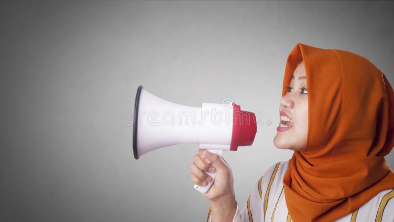 Young Asian businesswoman wearing suit and hijab screaming on megaphone with an angry expression. Close up body portrait veil muslim indonesian malaysian arab loudspeaker person female communication people corporate message shouting broadcasting formal manager speaking worker voice talking holding entrepreneur yelling attention news professional executive sound woman adult crazy job speech glasses employee cute. Young Asian businesswoman wearing suit and hijab screaming on megaphone with an angry expression. Close up body portrait veil muslim indonesian malaysian arab loudspeaker person female communication people corporate message shouting broadcasting formal manager speaking worker voice talking holding entrepreneur yelling attention news professional executive sound woman adult crazy job speech glasses employee cute