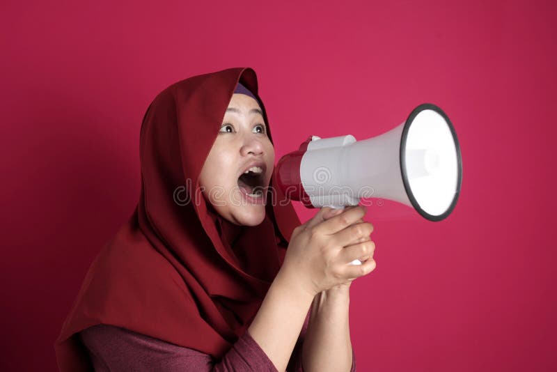Young Asian muslim businesswoman wearing hijab screaming with megaphone, angry expression. Close up body portrait. Young Asian muslim businesswoman wearing hijab screaming with megaphone, angry expression. Close up body portrait