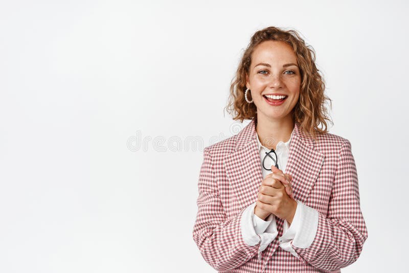 Young businesswoman clench hands, looking with hopeful face expression, smiling and looking at camera with anticipation