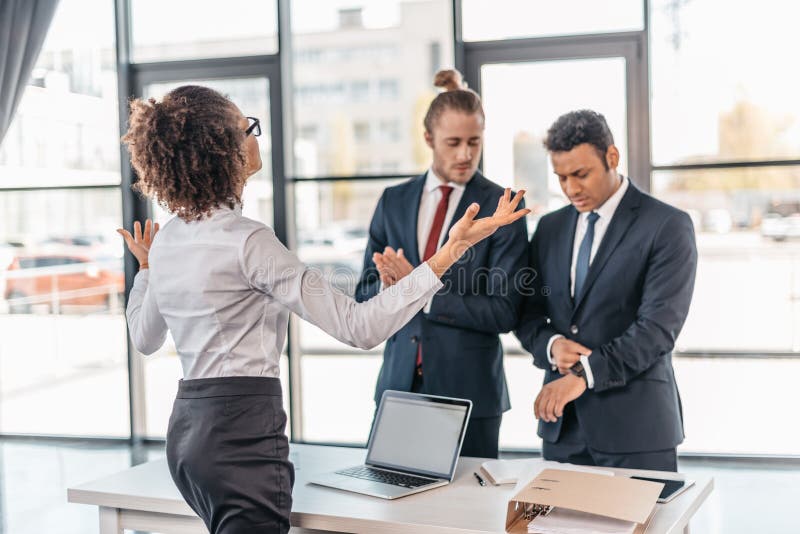 Young businesswoman gesturing and arguing with coworkers in office royalty free stock image Young businesswoman gesturing and arguing with coworkers in office royalty free stock image