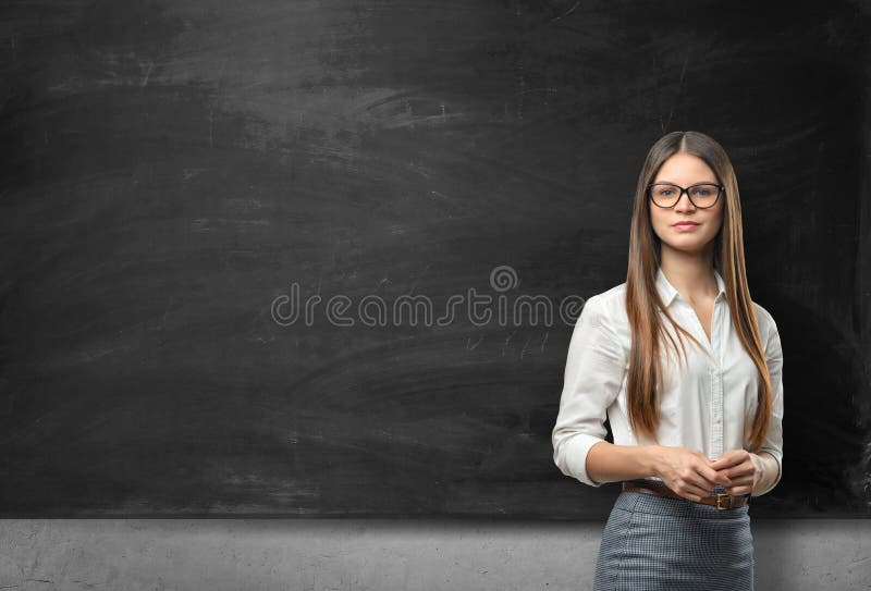 Young businesswoman with glasses standing in front of blank blackboard stock image Young businesswoman with glasses standing in front of blank blackboard stock image