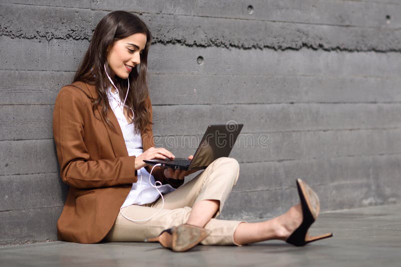 Young businesswoman sitting on floor looking at her laptop computer.