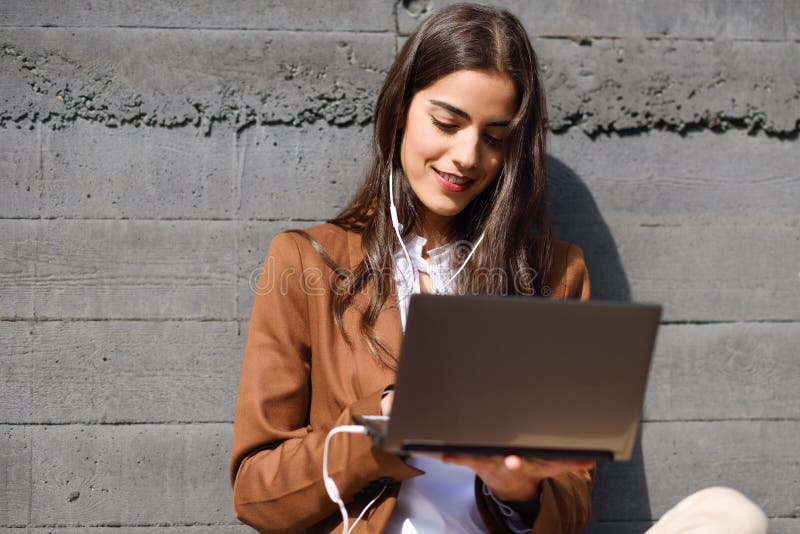 Young businesswoman sitting on floor looking at her laptop computer.