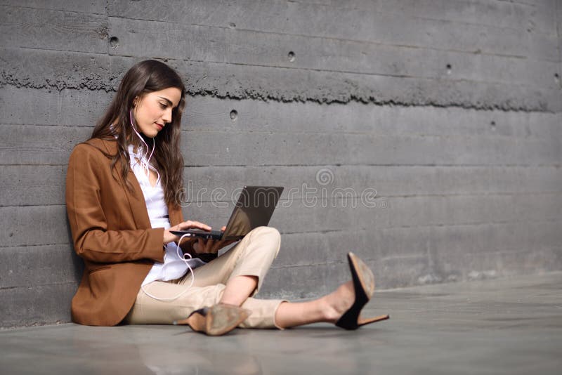 Young businesswoman sitting on floor looking at her laptop computer.