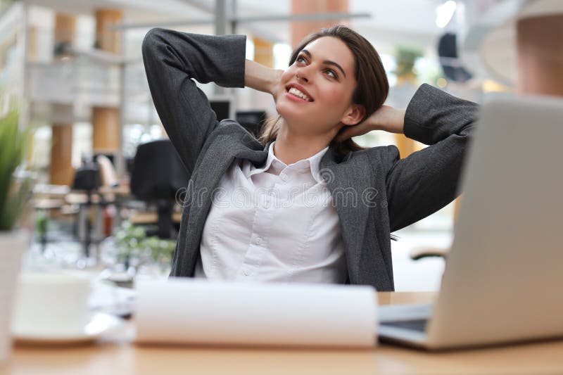 Young businesswoman sitting at office desk hold hands behind head relaxing feels good royalty free stock photo Young businesswoman sitting at office desk hold hands behind head relaxing feels good royalty free stock photo