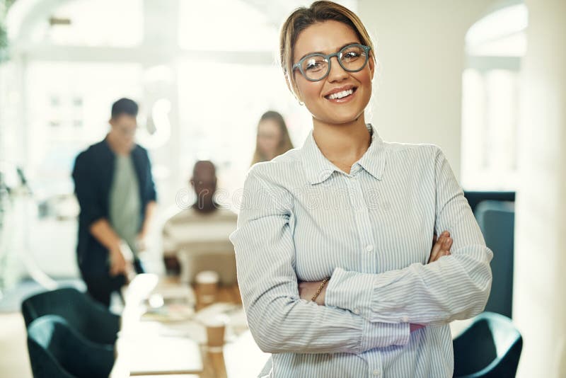 Young businesswoman standing in an office with colleagues behind royalty free stock photo Young businesswoman standing in an office with colleagues behind royalty free stock photo