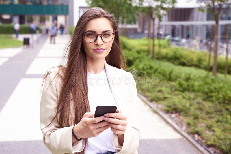 Young businesswoman text messaging while walking on the street in the city stock photography Young businesswoman text messaging while walking on the street in the city stock photography