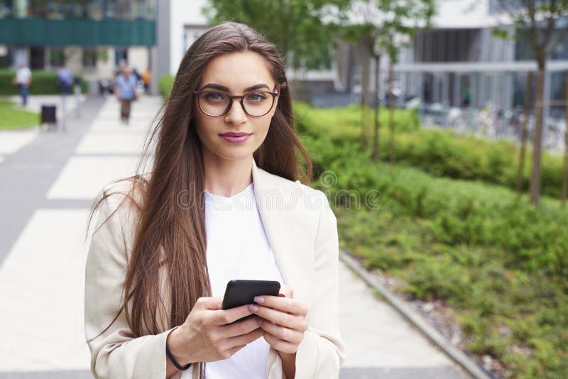 Young businesswoman text messaging while walking on the street in the city royalty free stock images Young businesswoman text messaging while walking on the street in the city royalty free stock images