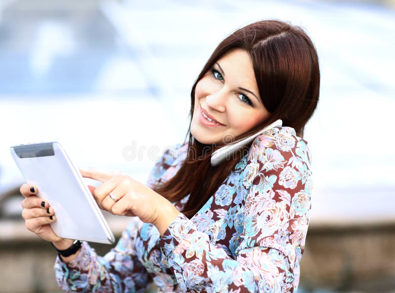 Young businesswoman using digital tablet and mobile phone over building background