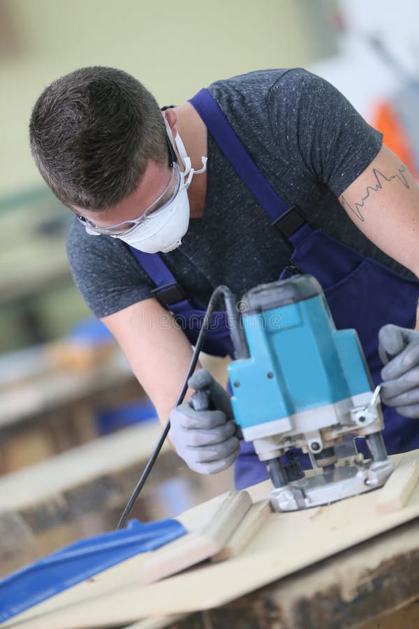 Young carpenter working on piece of wood with sawing machine. Young carpenter working on piece of wood with sawing machine