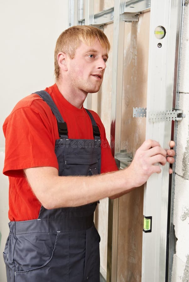 Young plasterer worker checking wall with level before wallboard installation. Young plasterer worker checking wall with level before wallboard installation