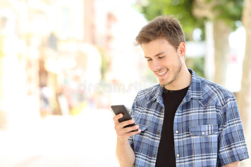 Young casual man using a smart phone texting messages in the street. Young casual man using a smart phone texting messages in the street