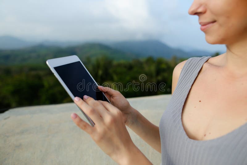 Young caucasian female person using tablet in ountains background. royalty free stock photography