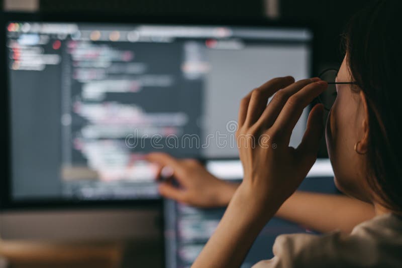 Young caucasian female programmer in glasses writes program code on a laptop stock photos