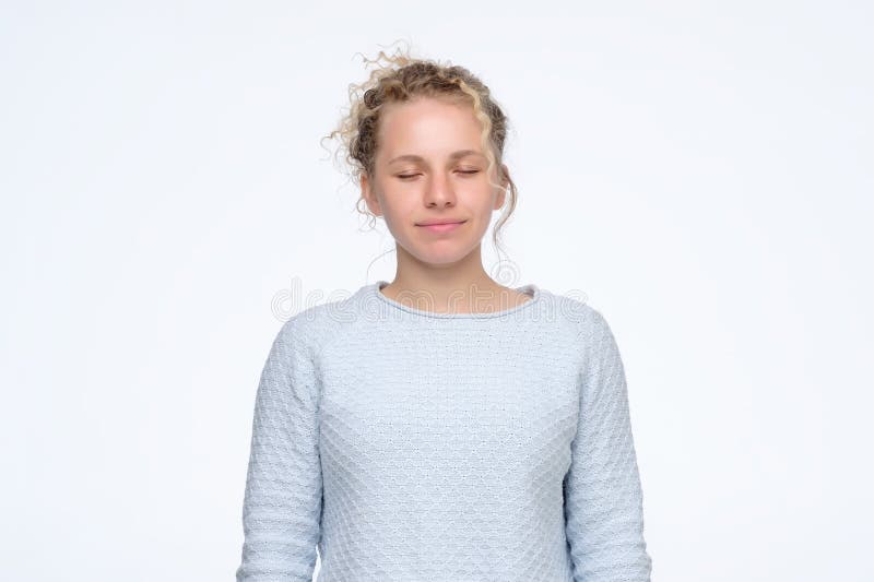 Young caucasian girl with curly hair standing with closed eyes with slight smile