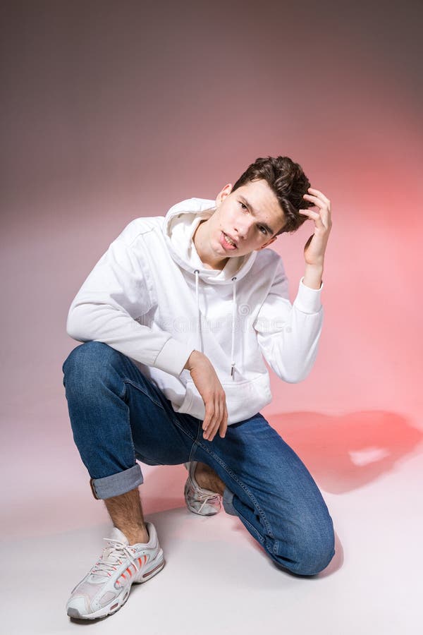 young caucasian male model posing sitting floor studio teenage boy stylish clothes pink background jeans guy 177974490