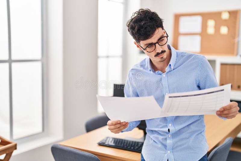 Young caucasian man business worker reading document at office royalty free stock photo