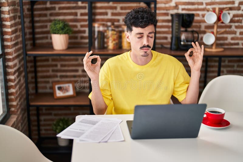Young caucasian man doing yoga exercise sitting on table at home royalty free stock image