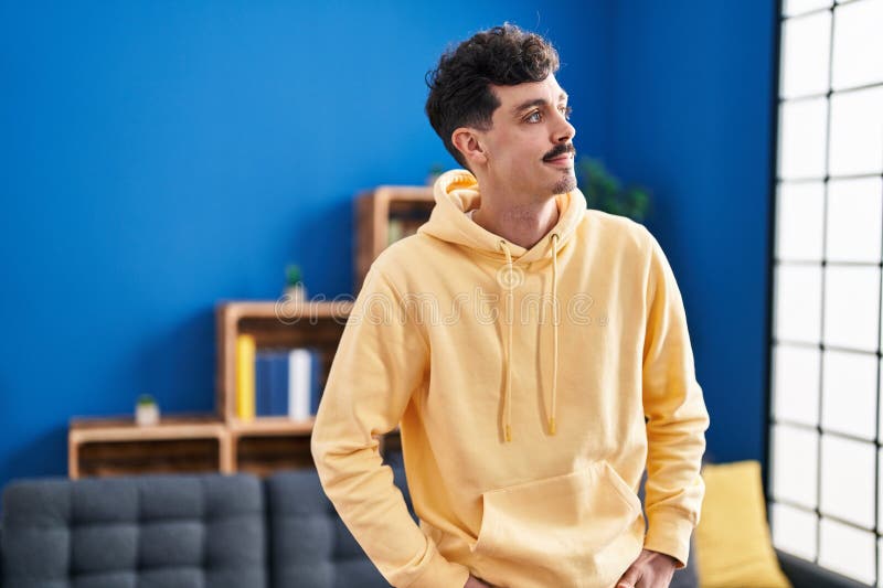 Young caucasian man smiling confident looking to the side at home stock photo